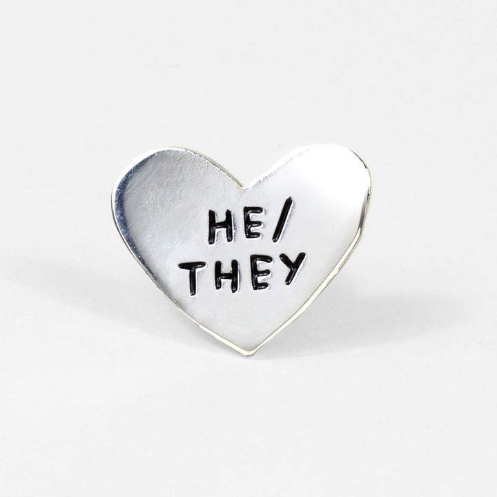 Pronoun Pins by Adam JK – Silver heart reads HE/THEY